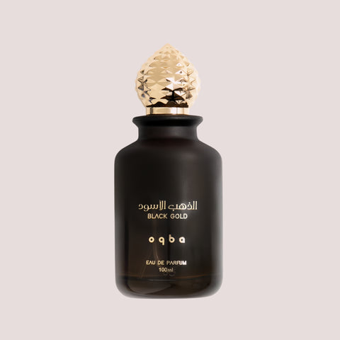 Black perfume bottle with gold cap on a light beige background