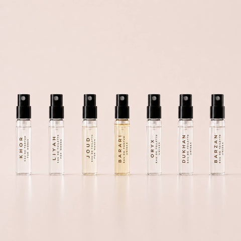 Row of perfume bottles with black caps on a beige background