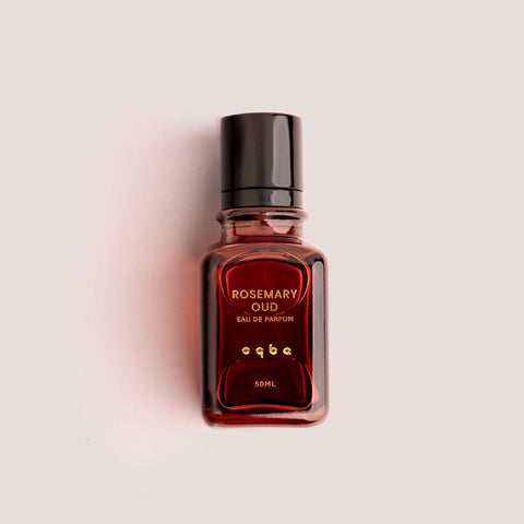 Perfume bottle labeled 'Rosemary Oud' by 'oqba' on a light pink background